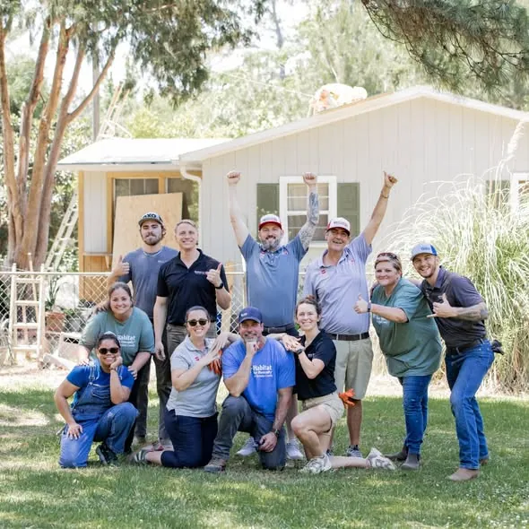 Volunteers and GAF team members celebrating outside a home on a Habitat for Humanity build day.
